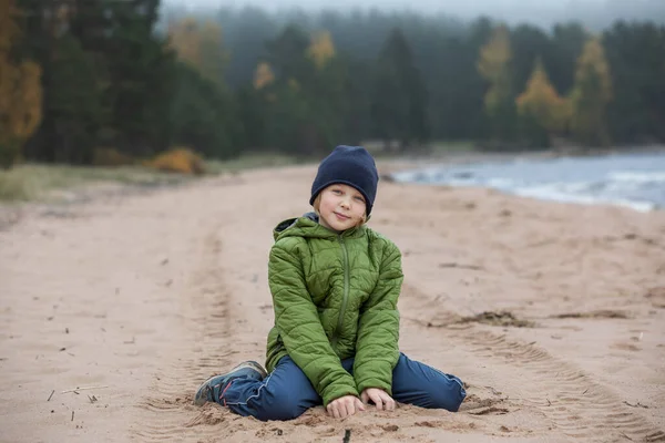 Retrato de uma rapariga de casaco na costa. Criança na praia junto ao mar frio. — Fotografia de Stock