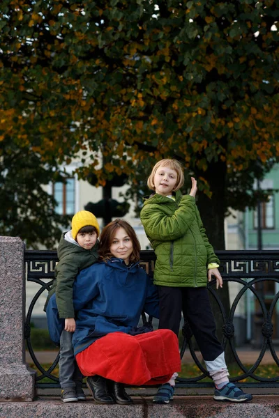 Rodina na procházce podél nábřeží města. Máma, dcera a syn se dívají do kamery a usmívají se. — Stock fotografie