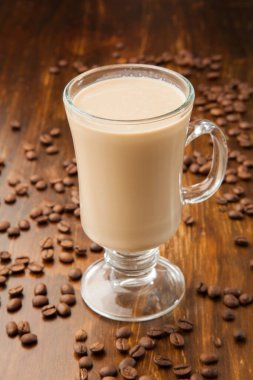 Etrafı kavrulmuş kahve çekirdekleriyle çevrili ahşap bir fonda nefis bir kahve..