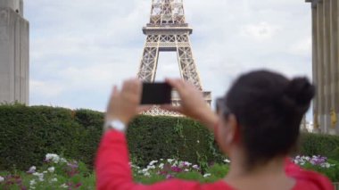 Kadın Eiffel Kulesi 'nin fotoğrafını çekiyor. Ağır çekimde akıllı telefon kullanıyor. 180 fp.