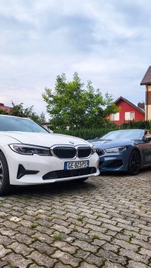 Vilnius, Litvanya - 2024-07-27 - Aile otoparkı BMW 3 serisi ve BMW 8 serisi özel ev bahçesinde