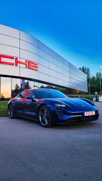 Vilnius, Litvanya - 2024-05-01 - Mavi lüks Porsche Taycan günbatımında bayiliğin önüne park edilmiş.