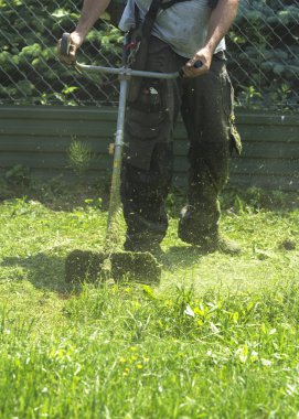Fırça kesici biçme makinesi veya güç aracı dize çim makası kullanarak adam yeşil biçme yabani ot bu alanın. Düzeltici ile bir çim biçmek için. Trimer bir çim mows. Bir çim bakımı.