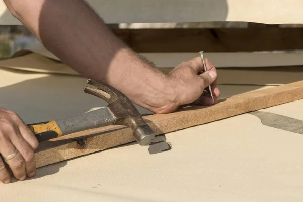 Roof construction building. Man hammering nails in to construction elements.