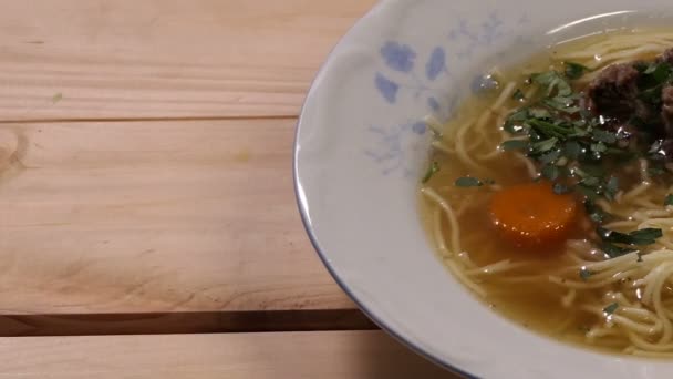 烹饪肉汤 在白色的盘子与肉 胡萝卜和面条在木背景的肉 胡萝卜和面条的肉汤 — 图库视频影像