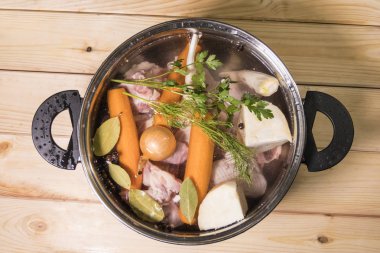 Ahşap masa üzerinde et suyu için malzemeler. Et, sebze ve otlar.