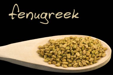 Çemen tahta kaşık siyah arka plan üzerine izole üzerinde. Latince adı Trigonella foenum-graecum