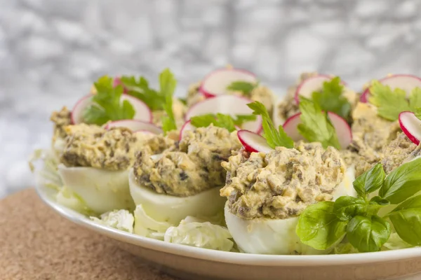 Haşlanmış yumurta champignon mantarları ile doldurulmuş ve turp, maydanoz, salata beyaz tabağa dilimlenmiş.