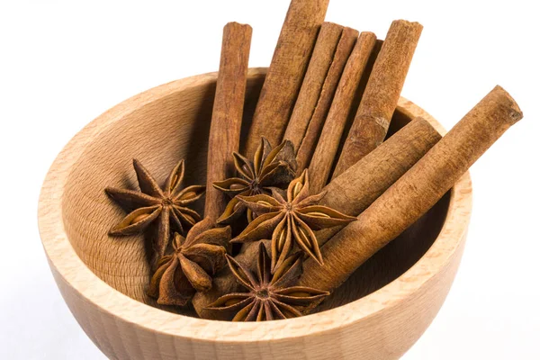 anise stars and cinnamon sticks in wooden bowl isolated on white background