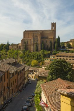 San Domenico Bazilikası 'nın mavi gökyüzüne karşı durduğu çatıların üzerindeki Siena şehir manzarası. Toskana, İtalya