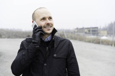 Smartphone açık havada üzerinde konuşurken siyah giysili adam portresi 