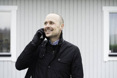 Smartphone açık havada üzerinde konuşurken siyah giysili adam portresi 