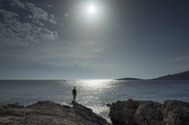 Adam gün batımında sahilde duruyor.