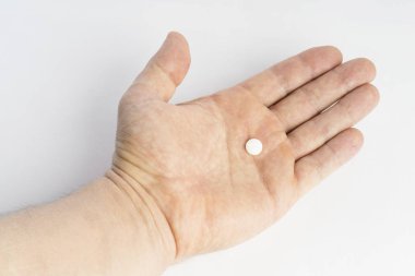 male hand holding pill on a light background