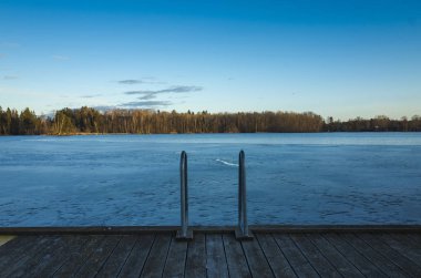 Bahar akşam İsveç İskandinavya Avrupa'nın güzel doğa ve manzara fotoğraf. Güzel taze mavi alacakaranlıkta gökyüzü günbatımı. Göl yansımaları, ahşap köprü ve ağaçlar ufuktan. Sakin, huzurlu fotoğraf