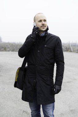 Adam akıllı telefon açık havada üzerinde konuşurken siyah giysili 