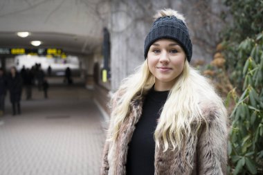 Güzel sarışın genç kadın ayakta açık havada giyen kürk ceket 