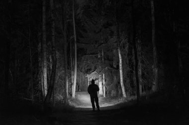 Man standing outdoors at night in tree alley shining with flashlight. Beautiful dark snowy winter night. clipart