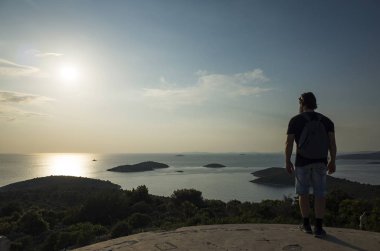 Sırt çantalı bir adam gün batımında sahilde