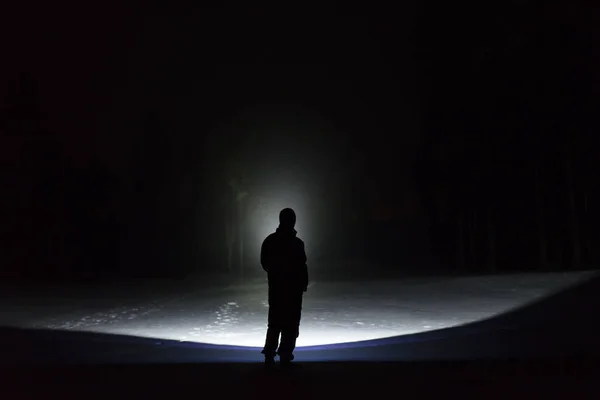 夜懐中電灯で輝いているツリー路地で屋外に立っている男性 雪に覆われた冬の美しい暗い夜 — ストック写真