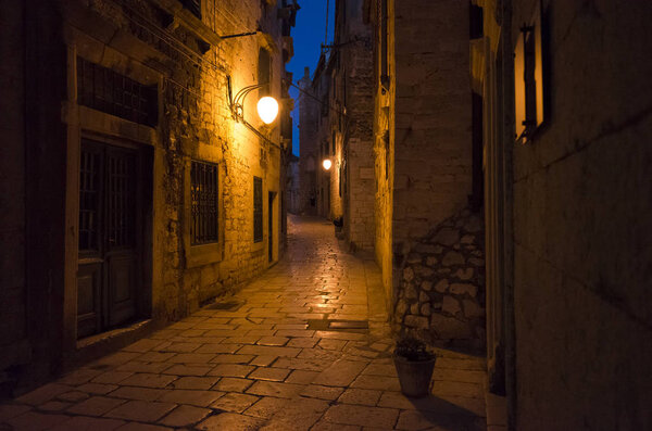 City of Sibenik Croatia Europe at night. Warm beautiful summer night with yellow and red color tones. Small alleys between houses and buildings at nice evening. Stone ground and walls