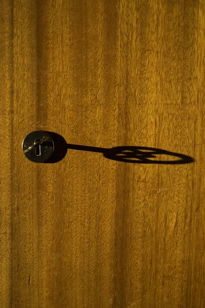 Ahşap kapı anahtar deliği anahtarında gölgesi. Güzel dokular, şekil ve ayrıntılar. Sakin, huzurlu renkli arka plan görüntüsü.