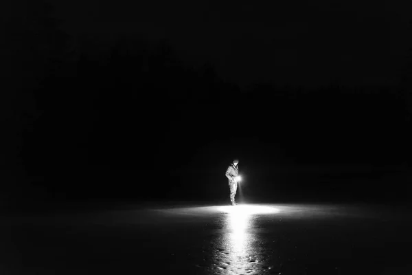夜屋外懐中電灯と前方に輝く森立っている男の人が 素敵な強い光ビーム 美しい抽象的な写真 穏やかな 静かな 神秘的なイメージ — ストック写真