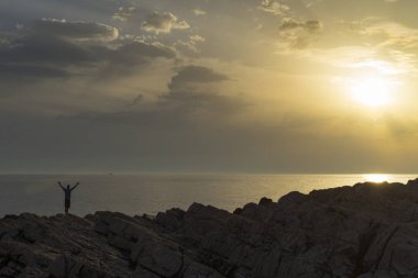 Adam ayakta yakın Hırvatistan Adriyatik Denizi günbatımı holding silah at. Güzel doğa ve manzara Dalmaçya kıyılarının. 