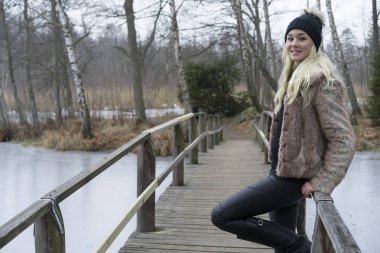 Güzel sarışın genç kadın ayakta açık havada giyen kürk ceket 