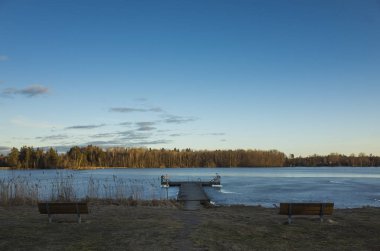 Bahar akşam İsveç İskandinavya Avrupa'nın güzel doğa ve manzara fotoğraf. Güzel taze mavi alacakaranlıkta gökyüzü günbatımı. Göl yansımaları, ahşap köprü ve ağaçlar ufuktan. Sakin, huzurlu fotoğraf
