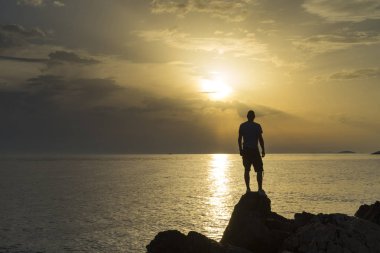 Adam ayakta yakın Hırvatistan Adriyatik Denizi günbatımı holding silah at. Güzel doğa ve manzara Dalmaçya kıyılarının. 