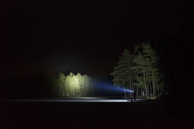 Adam açık havada ağaç arka sokakta el feneri ile parlayan geceleri ayakta. Güzel koyu karlı kış gecesi.