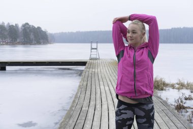 Genç kadın rahatlatıcı İsveçli kış manzara arka planda çalışmadan sonra buz Gölü 