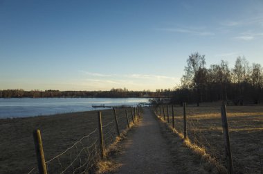 Bahar akşam İsveç İskandinavya Avrupa'nın güzel doğa ve manzara fotoğraf. Güzel taze mavi alacakaranlıkta gökyüzü günbatımı. Göl yansımaları, ahşap köprü ve ağaçlar ufuktan. Sakin, huzurlu fotoğraf