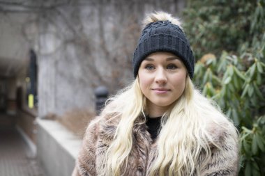 Güzel sarışın genç kadın ayakta açık havada giyen kürk ceket 