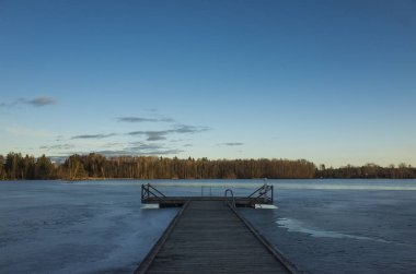 Bahar akşam İsveç İskandinavya Avrupa'nın güzel doğa ve manzara fotoğraf. Güzel taze mavi alacakaranlıkta gökyüzü günbatımı. Göl yansımaları, ahşap köprü ve ağaçlar ufuktan. Sakin, huzurlu fotoğraf