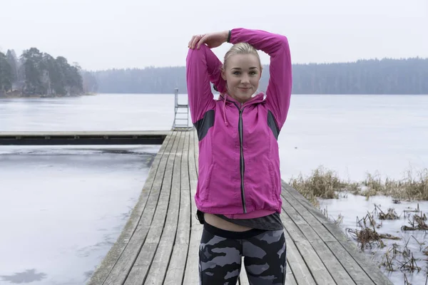 Genç kadın rahatlatıcı İsveçli kış manzara arka planda çalışmadan sonra buz Gölü 