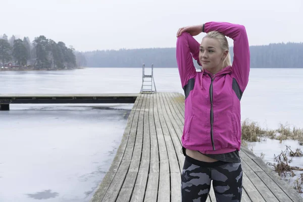 Genç kadın rahatlatıcı İsveçli kış manzara arka planda çalışmadan sonra buz Gölü 