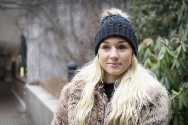 Güzel sarışın genç kadın ayakta açık havada giyen kürk ceket 