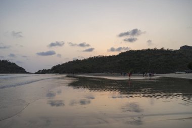 gün batımı sırasında kumlu plajda yürüyen insanların görünümü 
