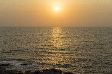 günbatımı arka planda kayalar ile kumlu plaj görünümü 