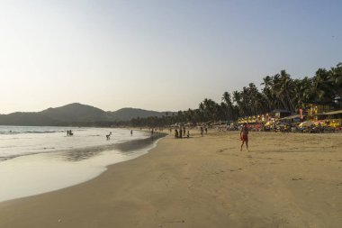 gün batımı sırasında kumlu plajda yürüyen insanların görünümü 