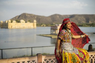 Jaipur, Rajasthan / Hindistan - 03: 25 2019, gün batımında Jal Mahal Sarayı, güzel elbiseli kadın pozu. Güzel detaylar ve renkler.
