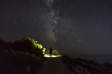 Razanj Hırvatistan 'daki karanlık gecenin güzel doğa ve manzara fotoğrafı. Adriyatik Denizi 'nde yıldızlı güzel bir gökyüzü. Dışarıda elinde fenerle dolaşan bir adam. Sakin, sakin açık hava görüntüsü.