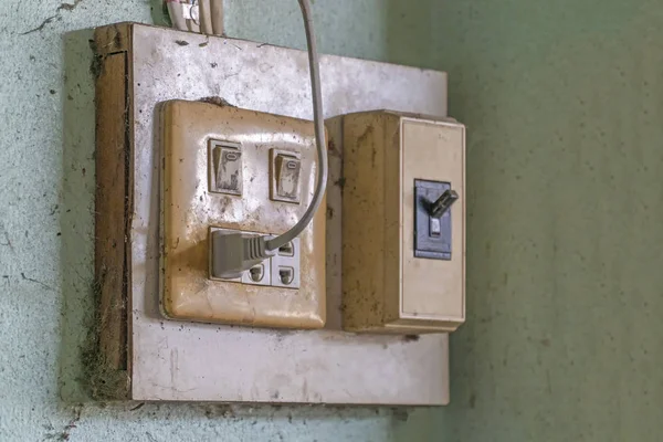 The old electrical plug next to the cream wall. — Stock Photo, Image