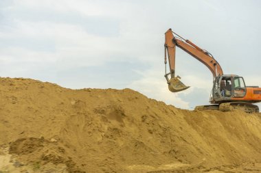 Sarı kepçe nehir kenarında ve yol kenarında çalışıyor.