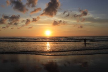 Endonezya 'da deniz ve plajın üzerinde güneş ve akşam gökyüzü batıyor