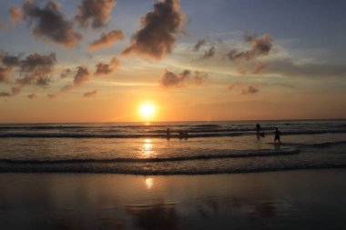 Endonezya 'da deniz ve plajın üzerinde güneş ve akşam gökyüzü batıyor