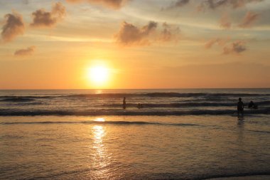 Endonezya 'da deniz ve plajın üzerinde güneş ve akşam gökyüzü batıyor