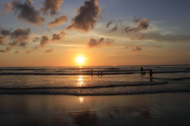 Endonezya 'da deniz ve plajın üzerinde güneş ve akşam gökyüzü batıyor